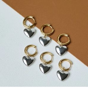 Macro detail of mixed metal gold hoop earrings with polished silver heart pendants