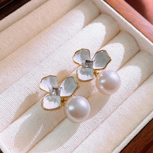 Dettaglio macro dell'orecchino a fiore bianco vintage con perla e bordi dorati