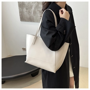 Minimalist white leather tote bag shown on model with black trench coat for daily commute