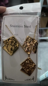 Macro detail of golden stainless steel square jewelry set with irregular leaf textures