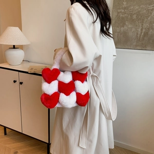 Plush heart patterned tote bag shown on model with chic beige coat in minimalist home setting