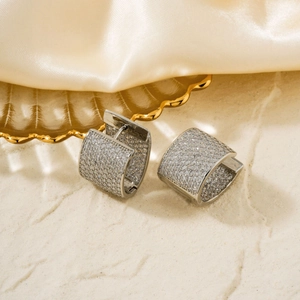 Détail de boucles d'oreilles créoles argentées en U avec zircons sur pierre et soie