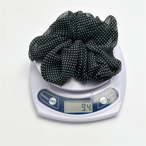 Polka dot mesh scrunchie in black and white being weighed on a digital scale