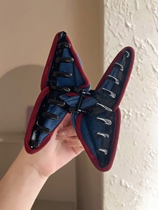 Detail of butterfly-shaped denim hair claw clip with contrast red piping and secure grip