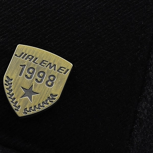 Macro shot of bronze metal shield badge with 1998 engraving on black winter baseball cap