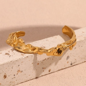 Detail of 18K gold plated stainless steel cuff featuring irregular hammered lava textures