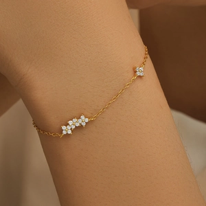 Close-up of gold chain bracelet with three diamond-studded floral petal charms