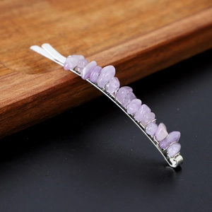 Detailed close-up of a metal hairpin featuring natural purple crystal gravel on wood