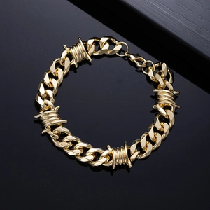 Detail of a gold Cuban link bracelet with barbed wire elements and lobster clasp closure