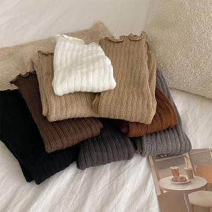 Detail of ribbed knit leg warmers in various colors including beige, grey and black