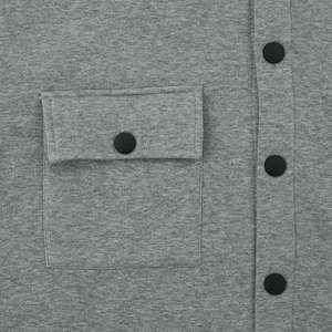 Detail of grey knitted jacket showing matte black snap buttons and pocket texture