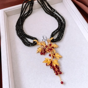 Detail of vintage multi-strand black beaded necklace with a golden grape pendant