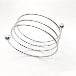 Close-up of silver multilayer spiral steel bracelet with polished lucky beads on ends