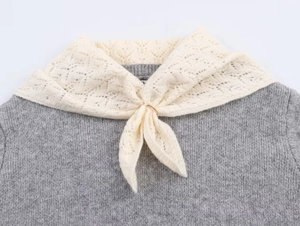 Detail view of grey knit sweater with lace collar and elegant gold metal ring buckle