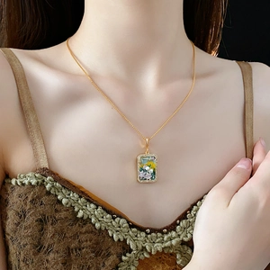 Detail of vintage gold flower pendant with green oil drip and freshwater pearl on model