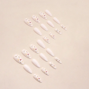 Almond-shaped press-on nails in creamy white with floral patterns and gold foil flakes