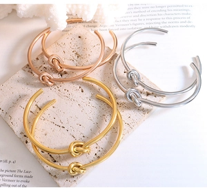 Detailed view of stackable knot open bangles in gold, silver, and rose gold finishes