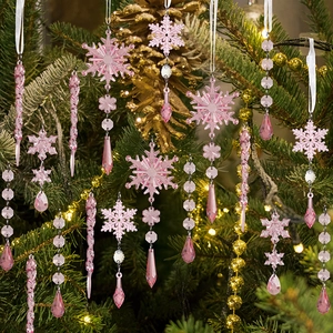 Pink acrylic snowflake and icicle ornaments hanging on a festive green Christmas tree