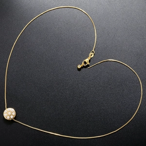 Macro detail of golden circular pendant with pearls arranged in a heart shape