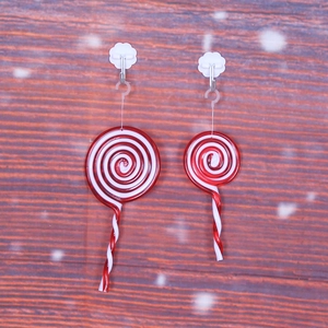 Red and white spiral Christmas lollipop ornaments hanging on a rustic wooden background