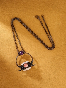 Detail view of retro bronze pendant with white crystal and amethyst on felt