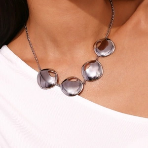 Close-up of polished irregular silver discs on a delicate stainless steel necklace
