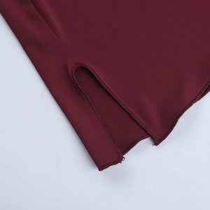 Close-up of the burgundy knit fabric texture and side slit hem detail of the dress