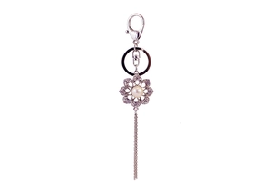 Detail of silver flower keychain with pearl center, rhinestone petals and long tassel
