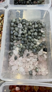 Close-up of 15mm heart-shaped natural crystals in pink and grey within a storage box