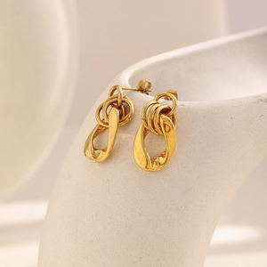 Detail of 18K gold-plated chain link earrings on a minimalist ceramic pedestal
