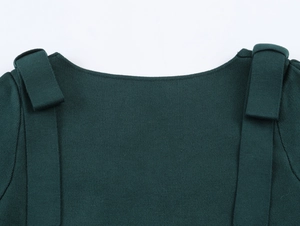 Detail of elegant off-shoulder knit top with shoulder ribbon design in dark green fabric
