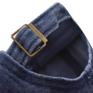 Detailed close-up of vintage bronze metal adjustable buckle on dark blue denim baseball cap