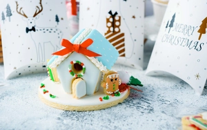 Detailed close-up of 3D Christmas gingerbread house cookie with blue roof and red bow