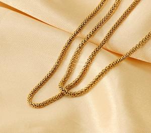 Close-up of 18K gold plated stainless steel mesh chain on soft silk fabric background