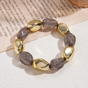 Close-up of bohemian irregular acrylic beads and gold metal spheres on a stylish bracelet