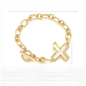 Detail of gold-plated stainless steel OT clasp bracelet with sparkling rhinestone cross