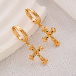 Detail of gold cross drop earrings with colorful crystals and embossed floral patterns