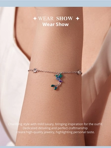 Silver hummingbird bracelet with teal enamel and sparkling zircons worn on wrist