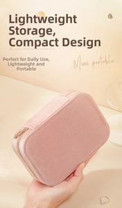 Compact pink velvet jewelry box held by hand featuring a gold zipper for travel storage