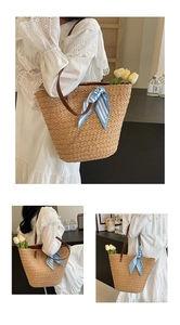 Detail of hand-woven straw tote bag featuring leather straps and striped silk scarf
