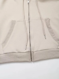 Dettaglio della cerniera metallica e dell'orlo della felpa sportiva con cappuccio beige