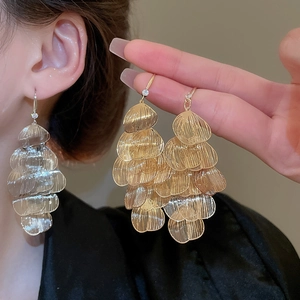 Detail of layered metal leaf earrings in gold and silver showing hollow textures