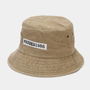 Detail of khaki washed cotton bucket hat showing FOUNDED1986 embroidery and metal eyelets