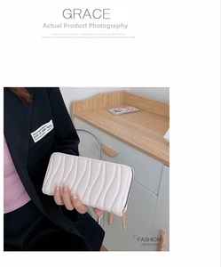 Detail of creamy white leather wallet with vertical wavy texture and gold zipper closure