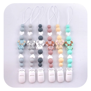 Flat lay of six colorful silicone pacifier clips with cute teddy bear charms on white background