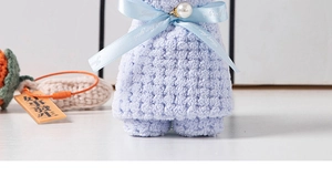 Detail of light purple coral fleece bear towel with blue ribbon and lucky charm gift