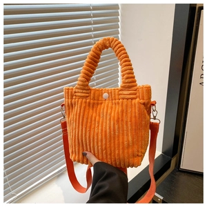 Detail of orange corduroy bucket bag texture with top handle and snap button closure