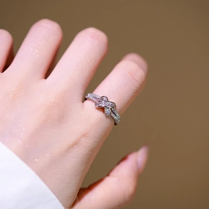 Crossed X-shape silver ring with pink and clear micro-set zircons on a model hand