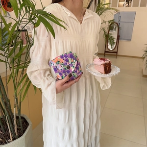 Mini floral fabric storage pouch with button closure held by woman in a cafe scene