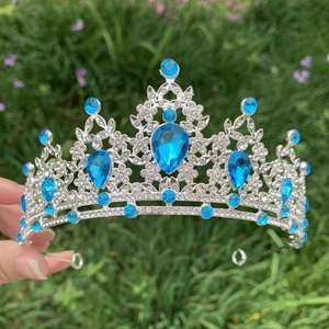 Detail of silver bridal crown with blue gemstones and rhinestones against a green lawn